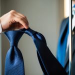 A silk tie being carefully folded and looped to create the perfect knot, with a mirror reflecting the process for precision